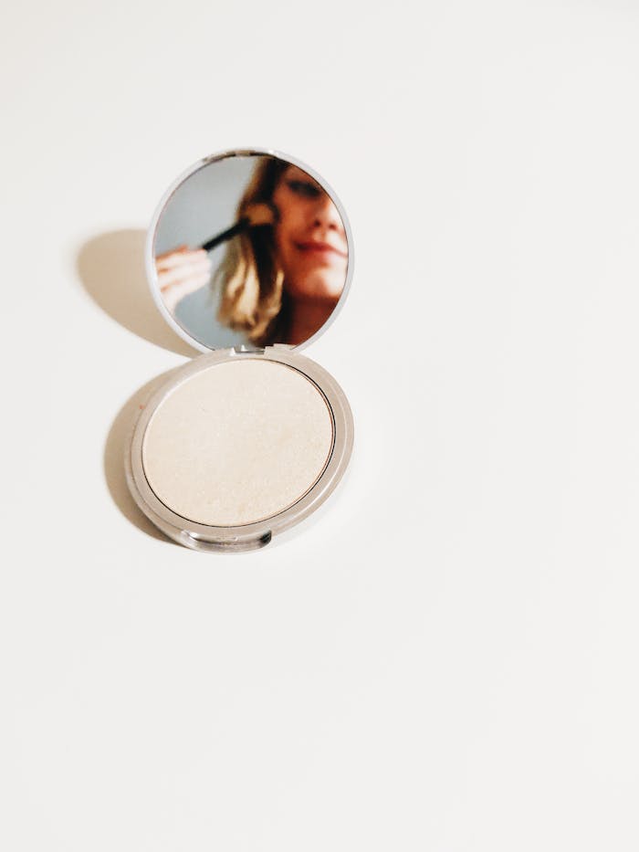 Elegant view of makeup application reflected in a compact mirror.